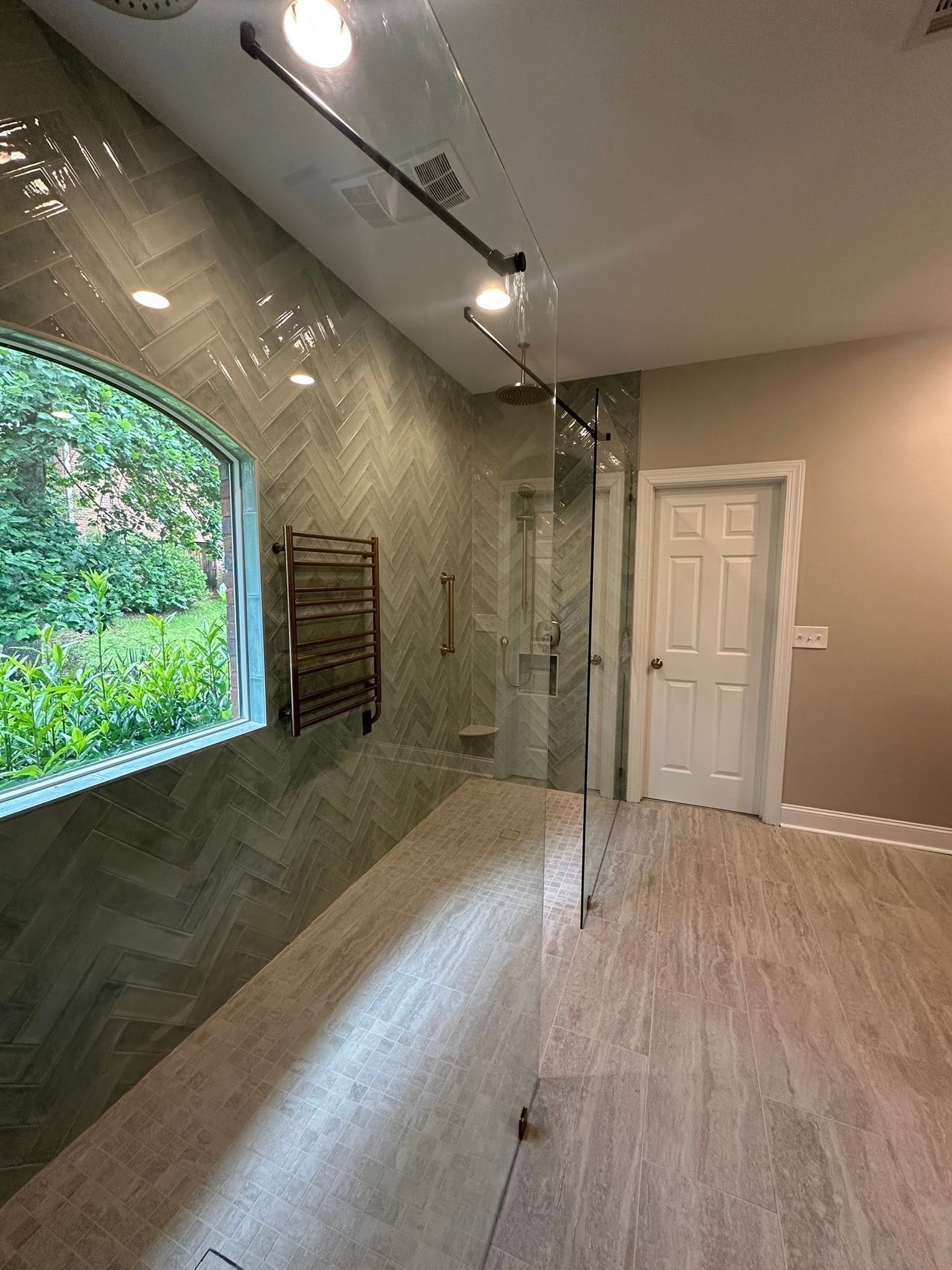 Custom herringbone tile multi-head walk-in shower with glass enclosure